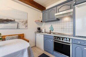 Une cuisine avec des meubles de couleur bleue, un lave-vaisselle, un four et une machine à café.