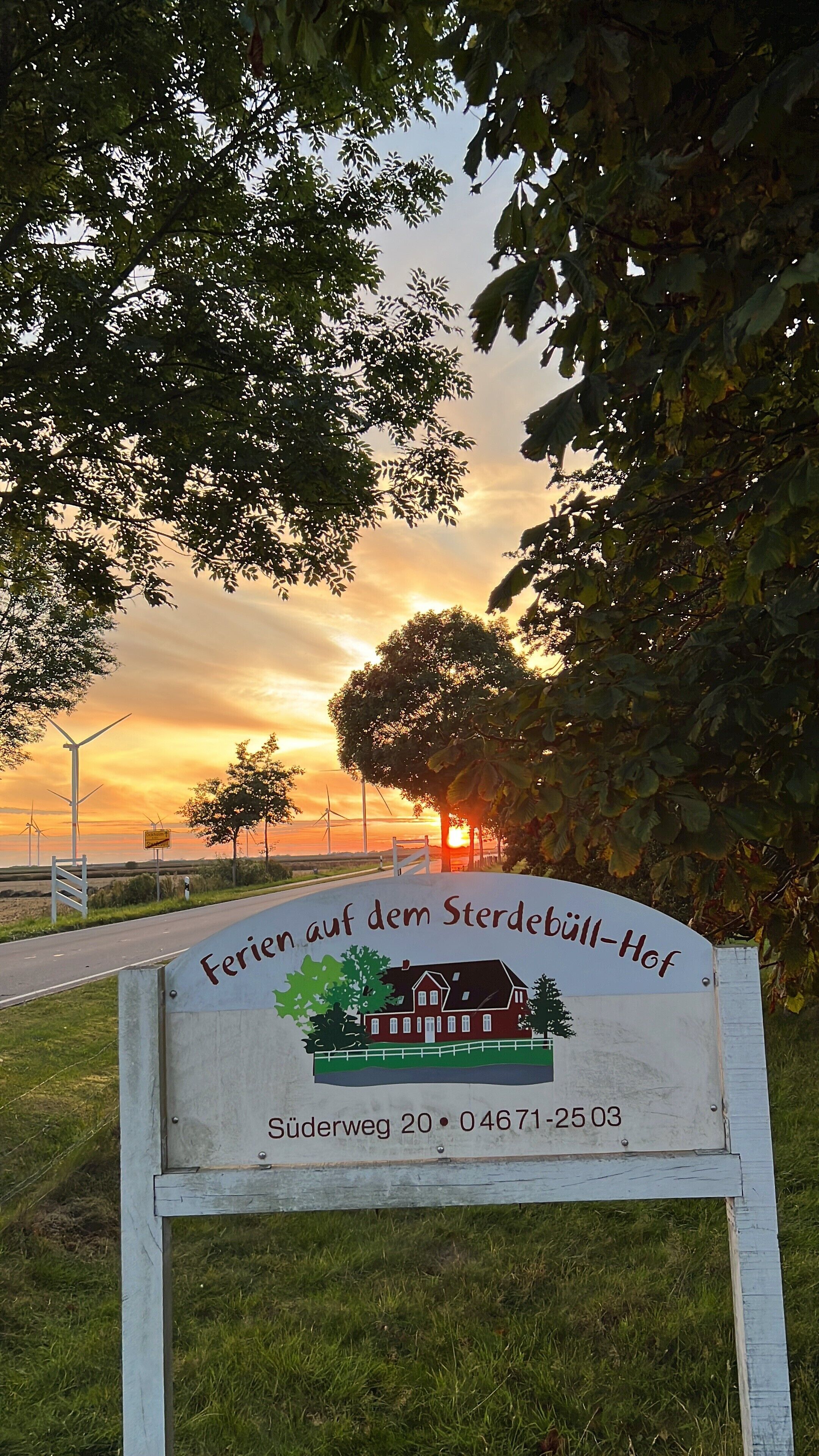 A sign for 'Ferien auf dem Sterdebell-Hof' with a house illustration, a street name, and a phone number.