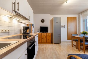 Moderni keittiö, jossa on liesi, uuni ja televisio.