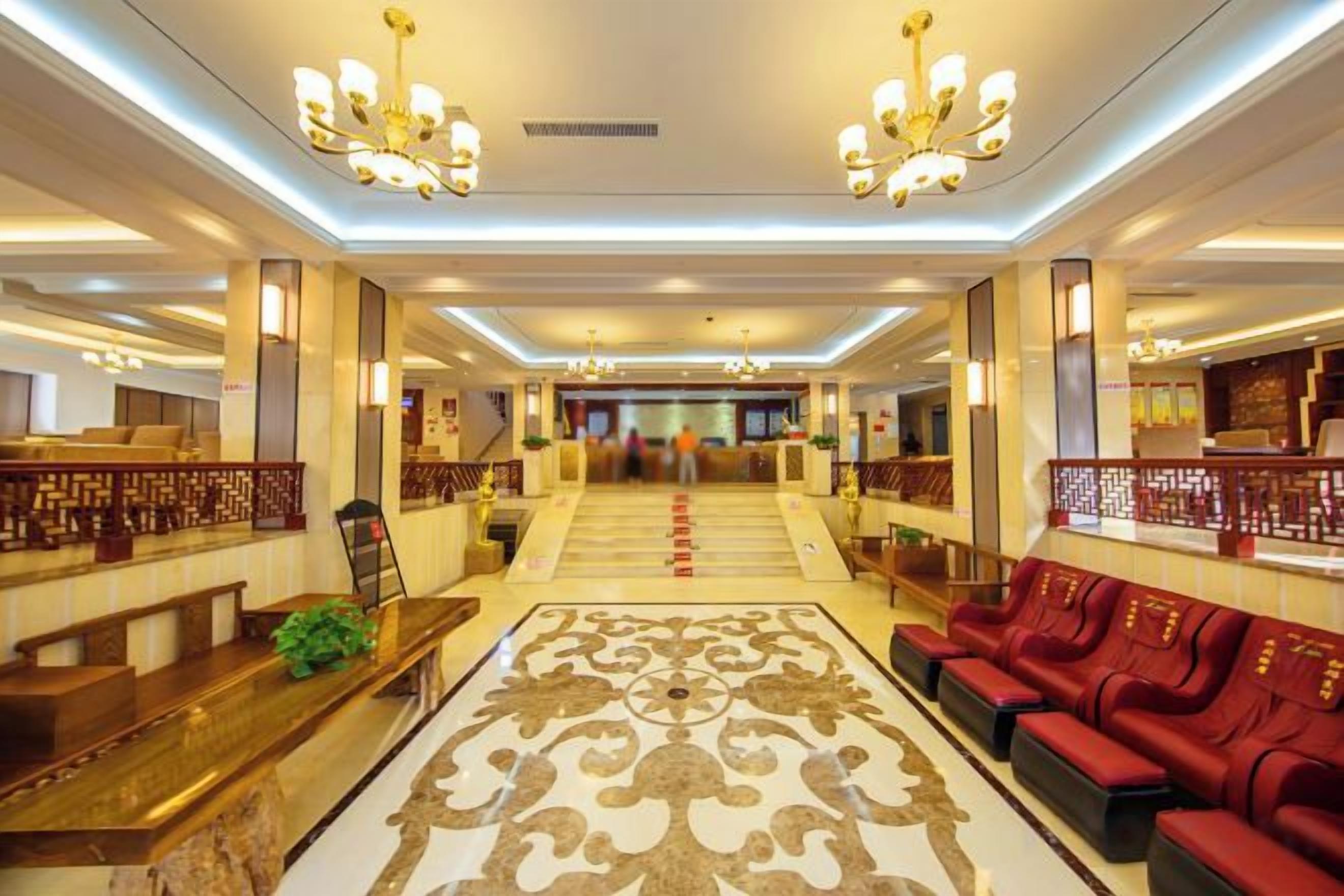 A hotel lobby with a grand staircase, seating areas, and a reception desk.