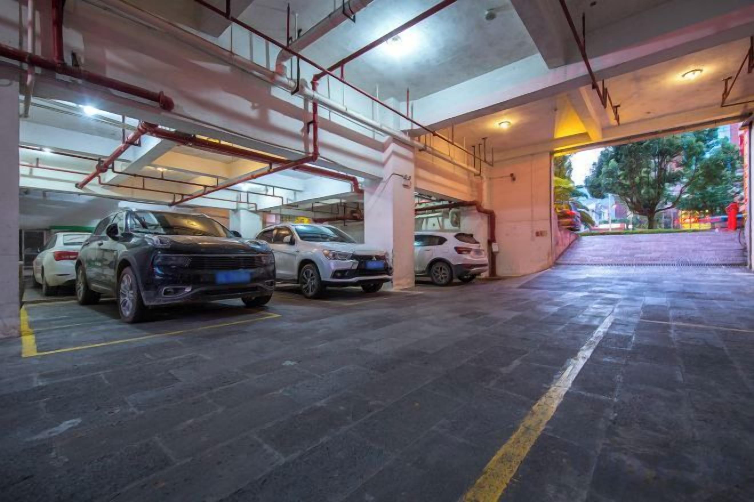 A multi-level parking garage with several cars parked, concrete floors, and visible structural beams.