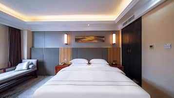 Habitación de hotel con una cama grande, una mesita de noche con lámpara, una obra de arte en la pared y un armario de color oscuro.