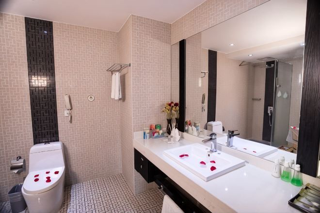 Un baño con inodoro, bidé, dos lavamanos, un espejo grande y zona de ducha.