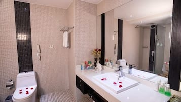 Un baño con inodoro, bidé, dos lavamanos, un espejo grande y zona de ducha.
