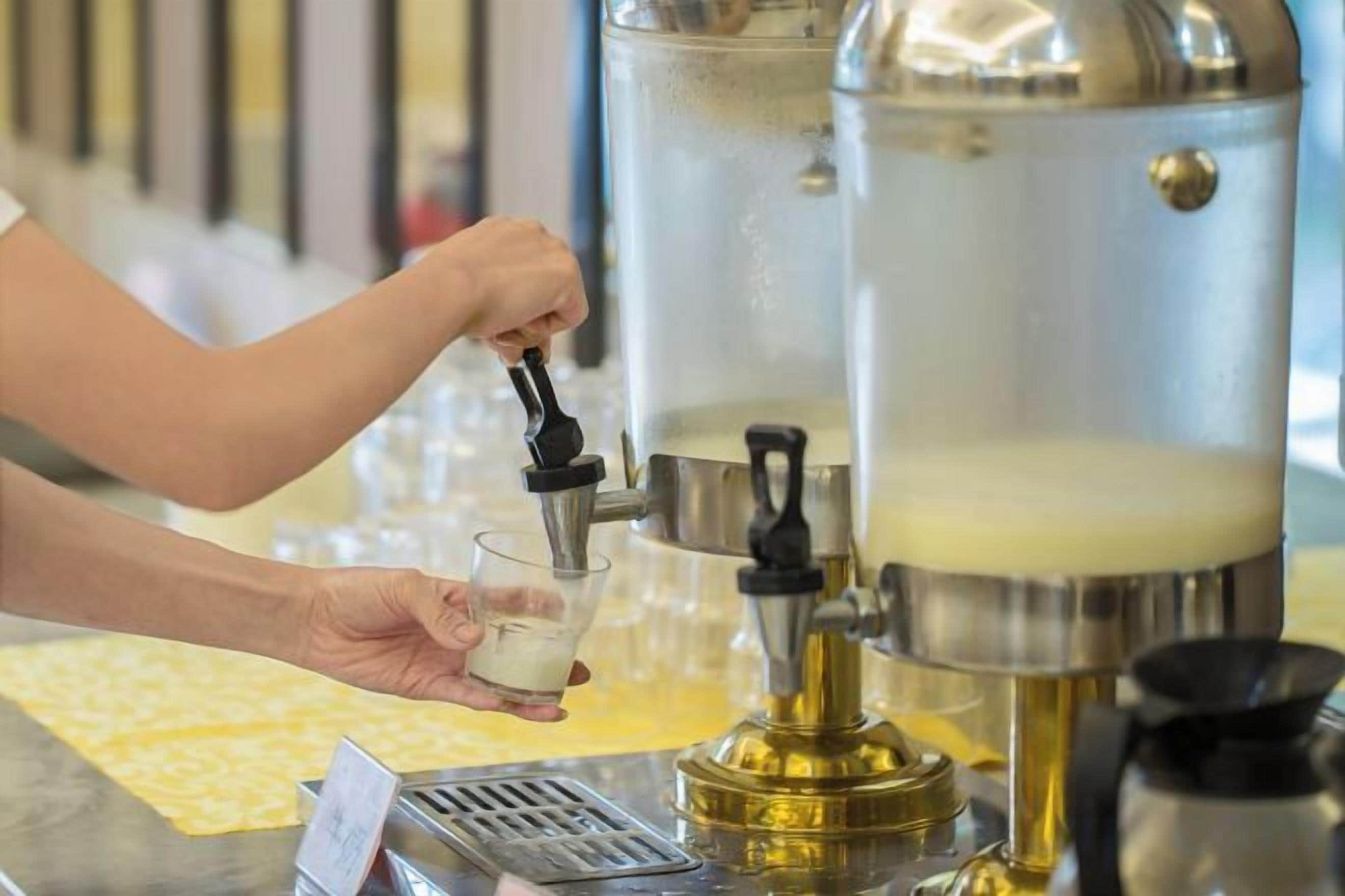 Una persona preparando café con una máquina, sirviéndolo en un vaso.