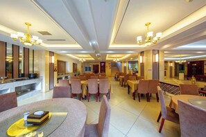 A spacious hotel dining area with multiple tables and chairs, a central bar, and a modern chandelier. - Mitin Holiday Hotel (Tengchong)