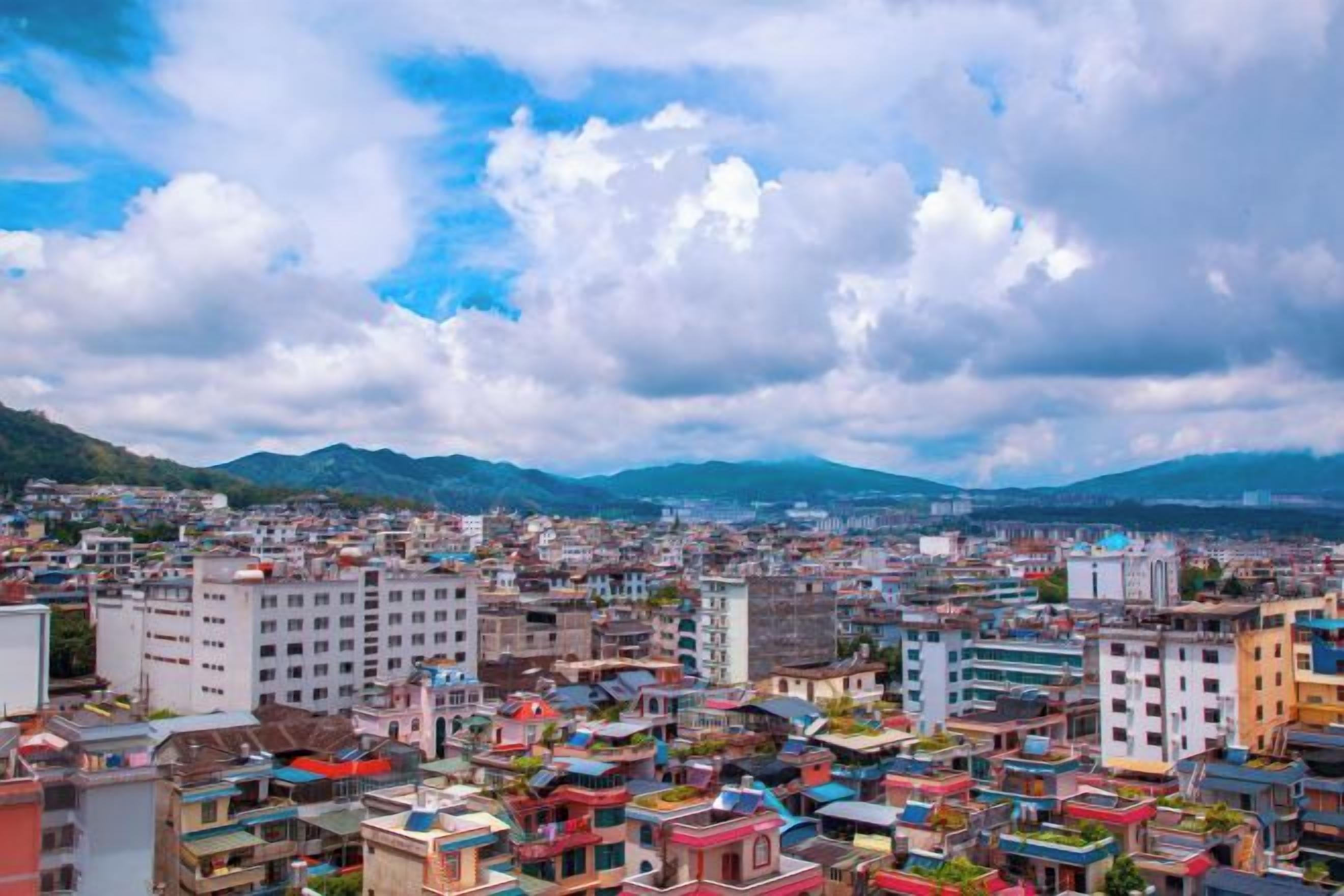 A densely packed urban area with a variety of building styles and a mountainous backdrop.
