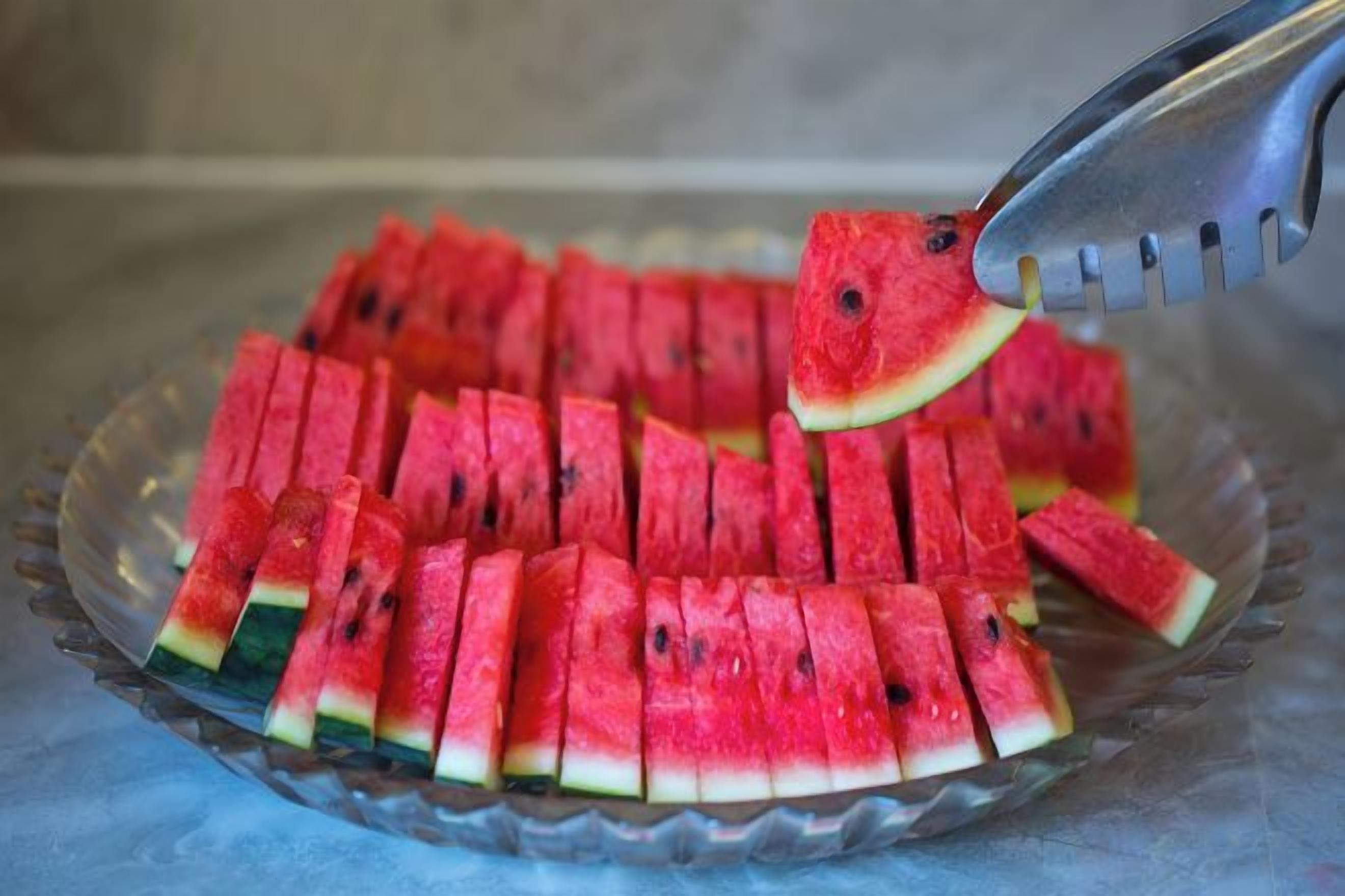 Une assiette en verre sur laquelle sont disposées des tranches de pastèque, présentées avec soin.