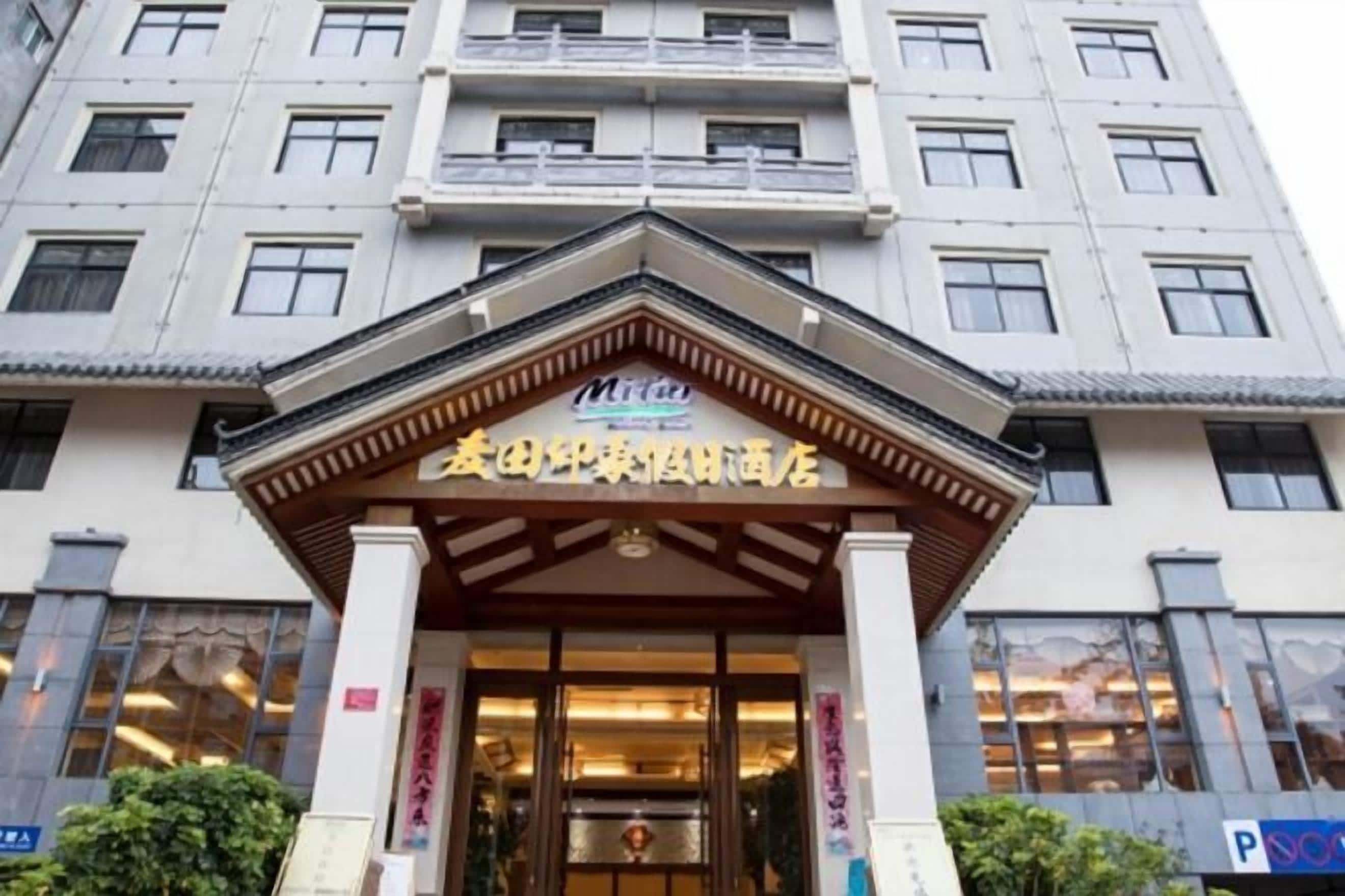 Entrada de hotel em estilo arquitetônico tradicional chinês, destacando um portal com toldo e colunas de madeira.