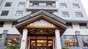 Entrada de hotel em estilo arquitetônico tradicional chinês, destacando um portal com toldo e colunas de madeira.