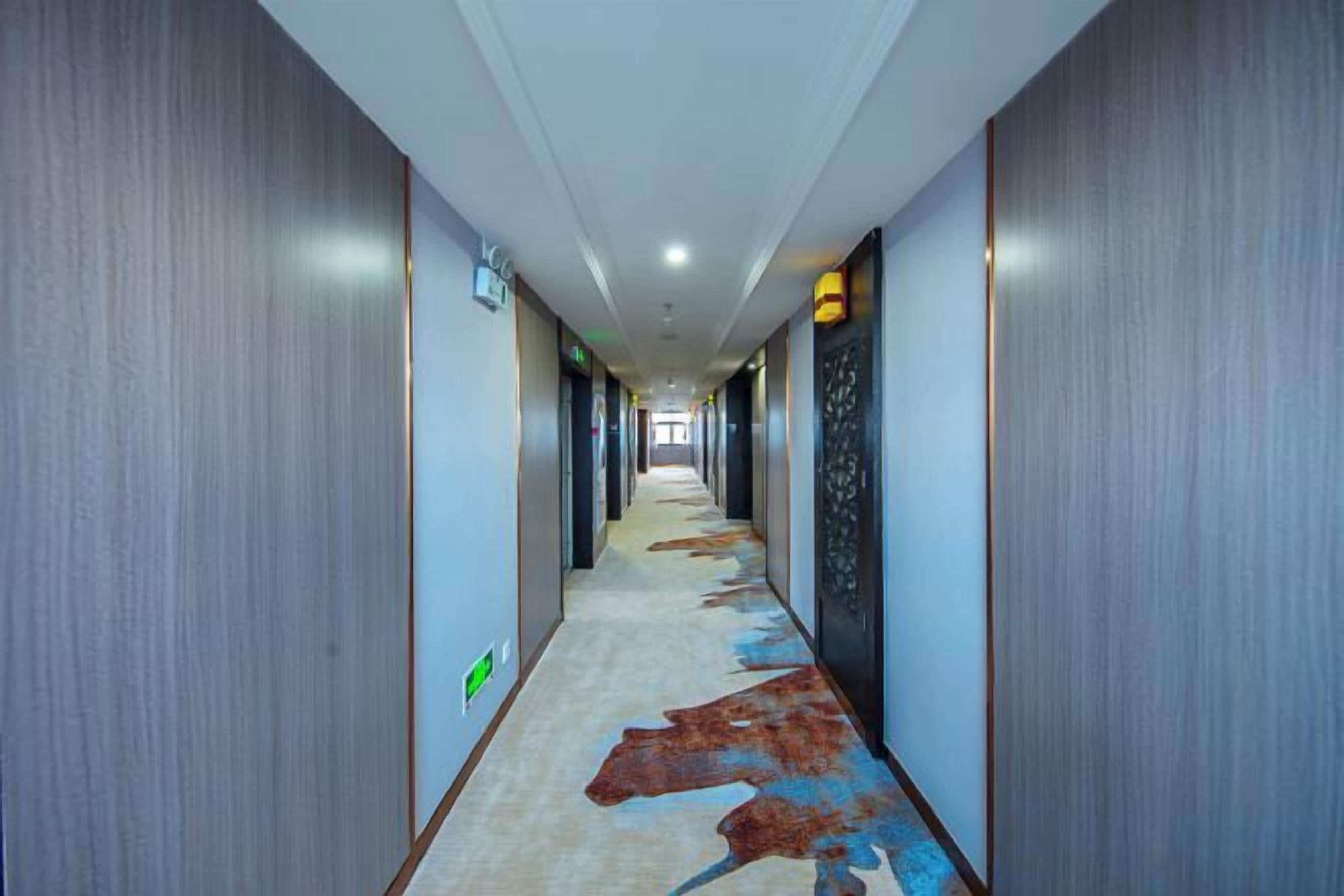 A hotel hallway with a carpet featuring a cow print design, wooden walls, and a ceiling with recessed lighting.