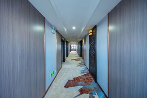 A hotel hallway with a carpet featuring a cow print design, wooden walls, and a ceiling with recessed lighting. - Mitin Holiday Hotel (Tengchong)