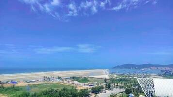 Eine Küstenansicht mit Strand, einem modernen Gebäude und wolkenlosem Himmel.