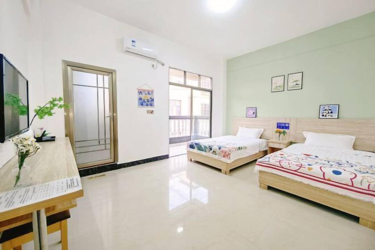A hotel room with two beds, a desk with a chair, a TV, and a window.