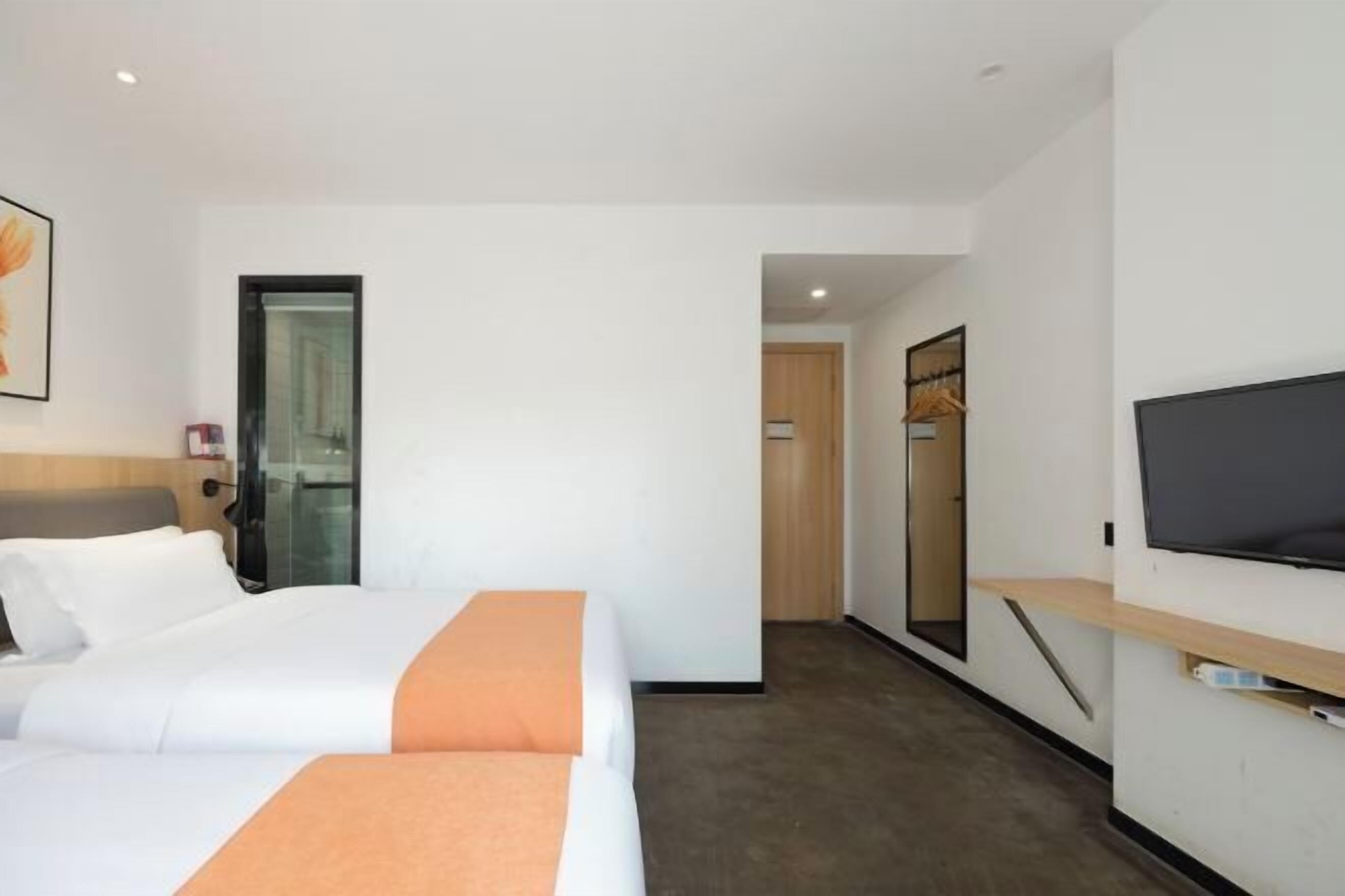 Una habitación de hotel con cama, televisión, armario y una puerta que da a otra habitación.