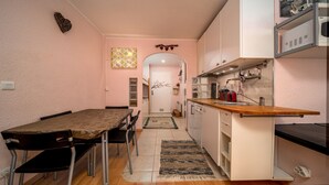 A compact kitchen with a dining area, featuring a wooden table, chairs, and a kitchen counter with appliances. - Magnificent 4-pers studio with fireplace (Allos)