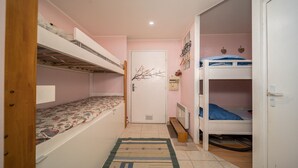 A narrow room with two bunk beds, a door with a floral decal, and a radiator on the wall. - Magnificent 4-pers studio with fireplace (Allos)