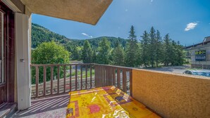A balcony with a view of a forested mountain and a building with a sign. - Magnificent 4-pers studio with fireplace (Allos)