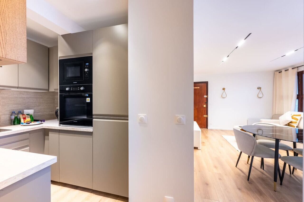 Una cocina moderna con electrodomésticos integrados y un comedor con mesa y sillas de vidrio.
