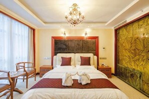 Une chambre d’hôtel avec un grand lit, un lustre, un bureau et une chaise.