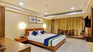 A hotel room with a large bed, bedside tables, a desk, and a TV. - Hotel Apollo Grand (Guwahati)
