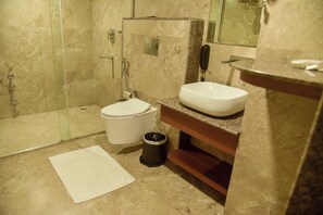 A modern bathroom with a glass-enclosed shower, a white sink, and a marble-tiled floor. - Hotel Apollo Grand (Guwahati)
