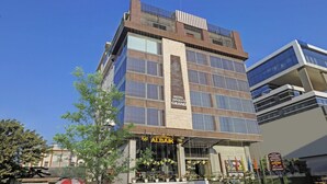 A multi-story hotel with a prominent sign for 'Hotel Apollo Grand' and 'Al Baik' on the ground floor. - Hotel Apollo Grand (Guwahati)