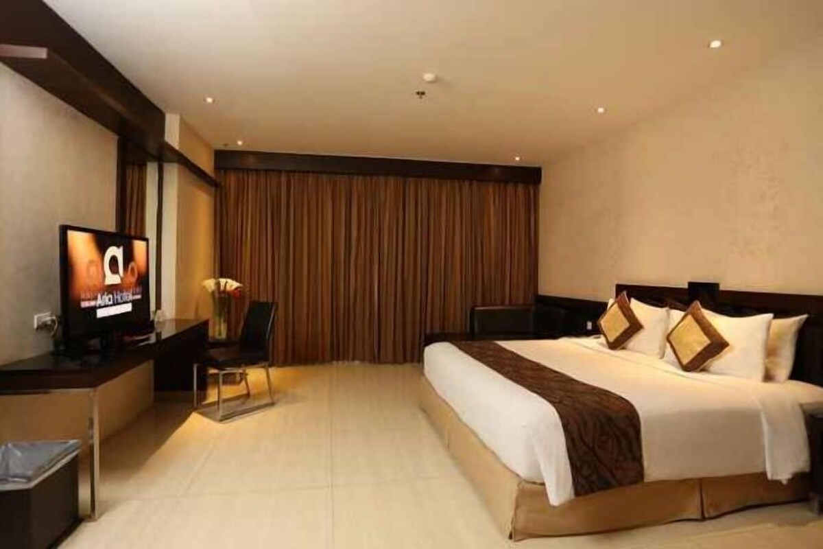 Ein Hotelzimmer mit einem großen Bett, einem Schreibtisch mit Fernseher und Blick nach draußen.