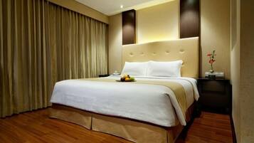 A hotel room with a large bed, a bedside table, a nightstand, and a curtain.