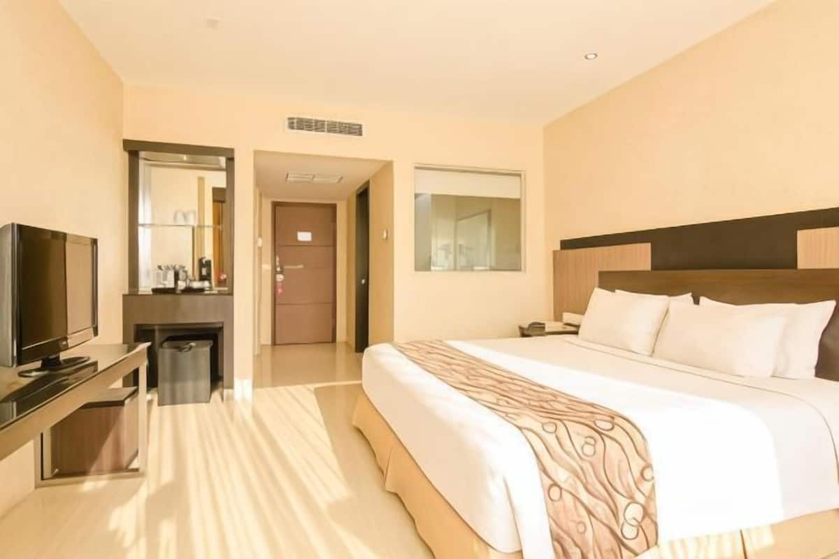 A hotel room with a bed, a TV, a desk, and a mirror.