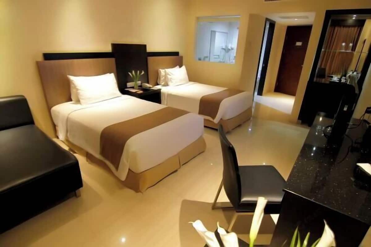 A hotel room with two beds, a desk, and a chair.
