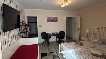 Habitación de hotel con cama, escritorio con dos sillas, televisor y puerta que da a otra habitación.
