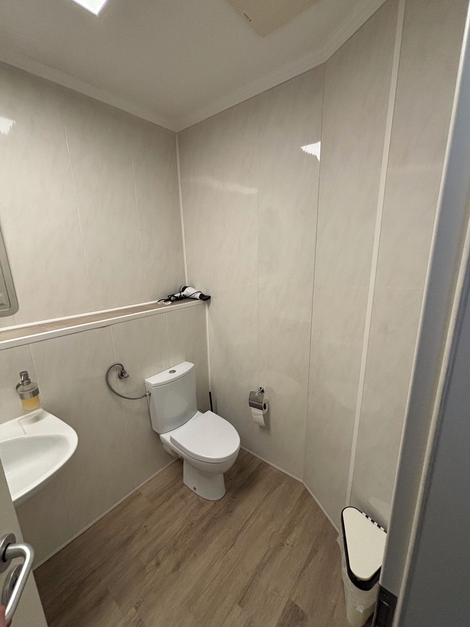 A small, modern bathroom with a toilet, sink, and shower.