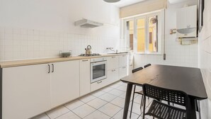 Una cocina con armarios blancos, encimera de madera, estufa y mesa de comedor con sillas.