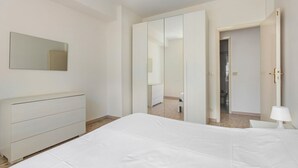 Un dormitorio con cama, cómoda, espejo y armario.