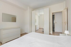 Quarto com cama, cômoda, espelho e guarda-roupa.