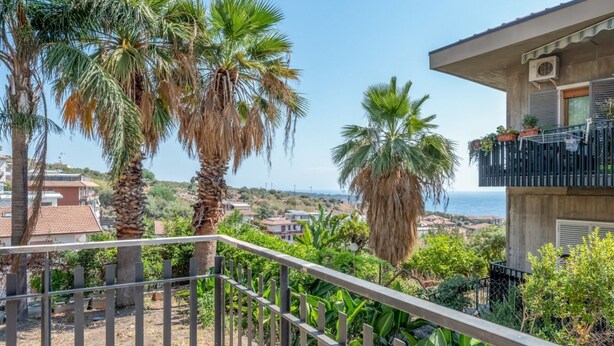 Un balcón con vista a palmeras y al mar.