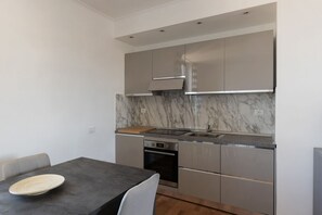 A modern kitchen with a marble backsplash, stainless steel appliances, and a dark countertop.