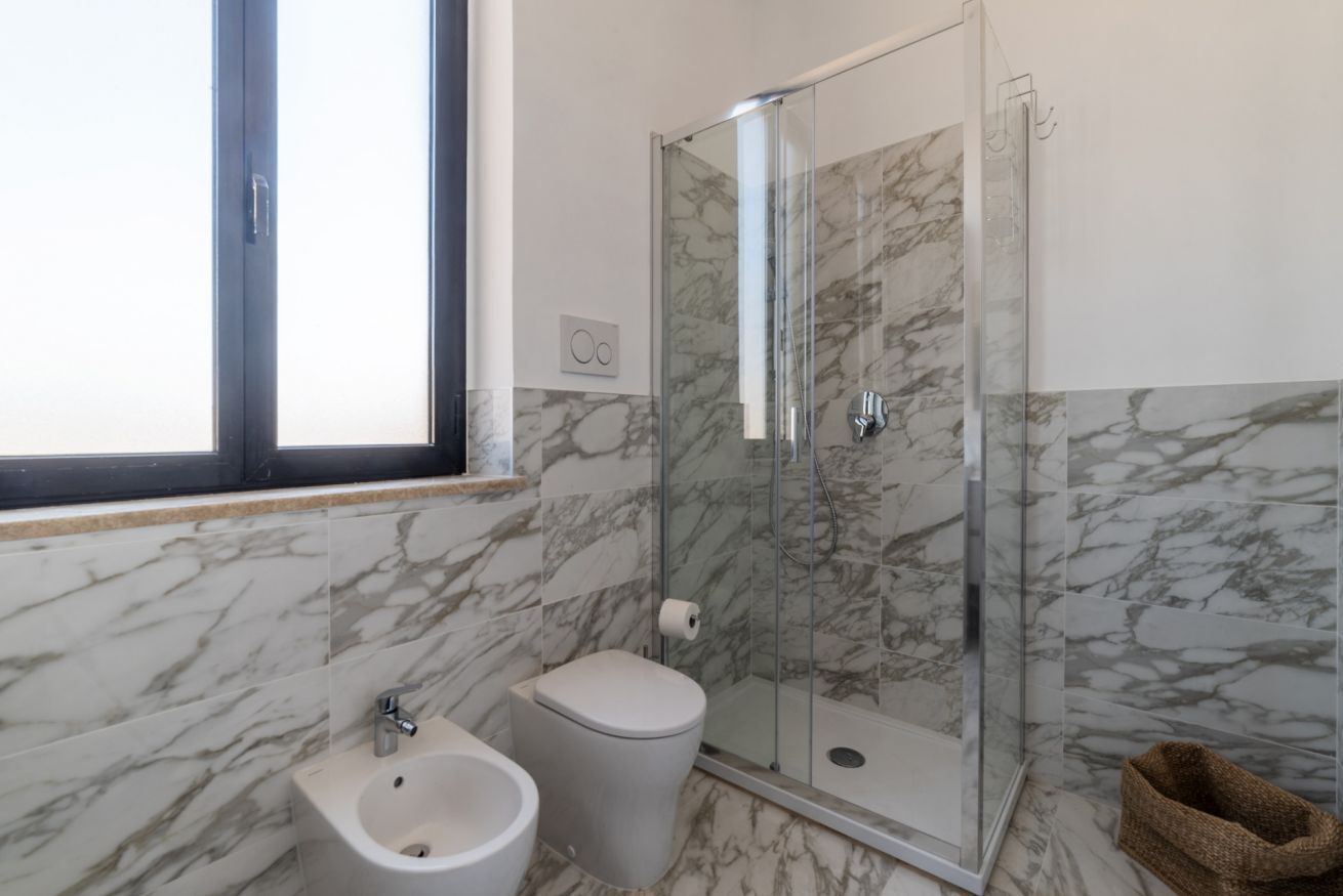 A bathroom with a bidet, toilet, and glass-enclosed shower.