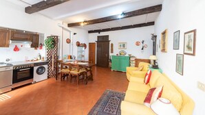 A kitchen with modern appliances, a dining area with wooden furniture, and a living room with a yellow sofa.