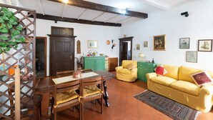 A dining area with a wooden table and chairs, a green cabinet, and a yellow sofa.