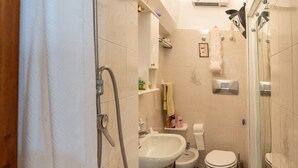 A bathroom with a shower, bidet, toilet, and sink.