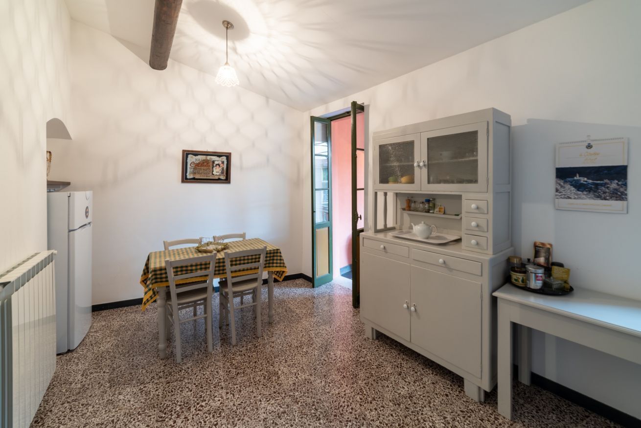 Une cuisine équipée d’une table et de chaises, d’un réfrigérateur, d’un meuble avec des portes en verre et d’une fenêtre.