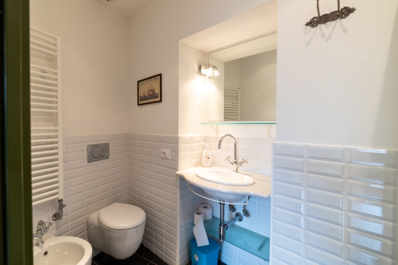 A bathroom with a toilet, sink, and mirror.