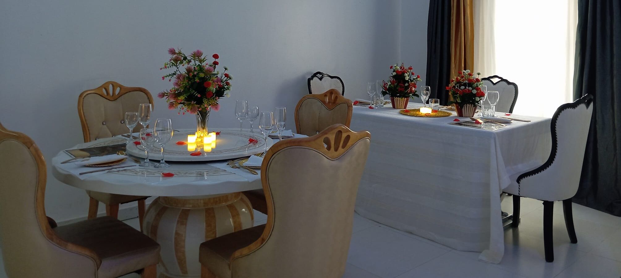 A dining area with round tables, chairs, and floral centerpieces.