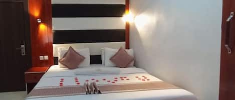 Una cama bien hecha con un cabecero a rayas, una mesita de noche y una lámpara de pared.