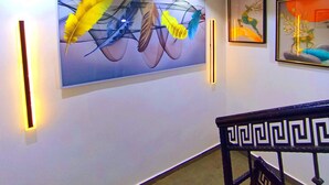 Un corridoio con un'ampia pittura astratta, una scala con ringhiera geometrica e opere d'arte incorniciate alle pareti.