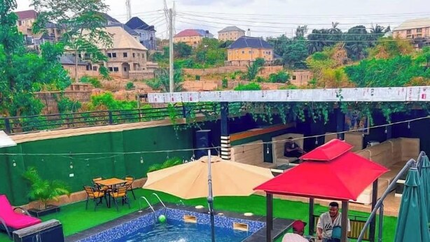 Una piscina con un'area di prato sintetico verde, circondata da posti a sedere e ombrelloni da esterno.
