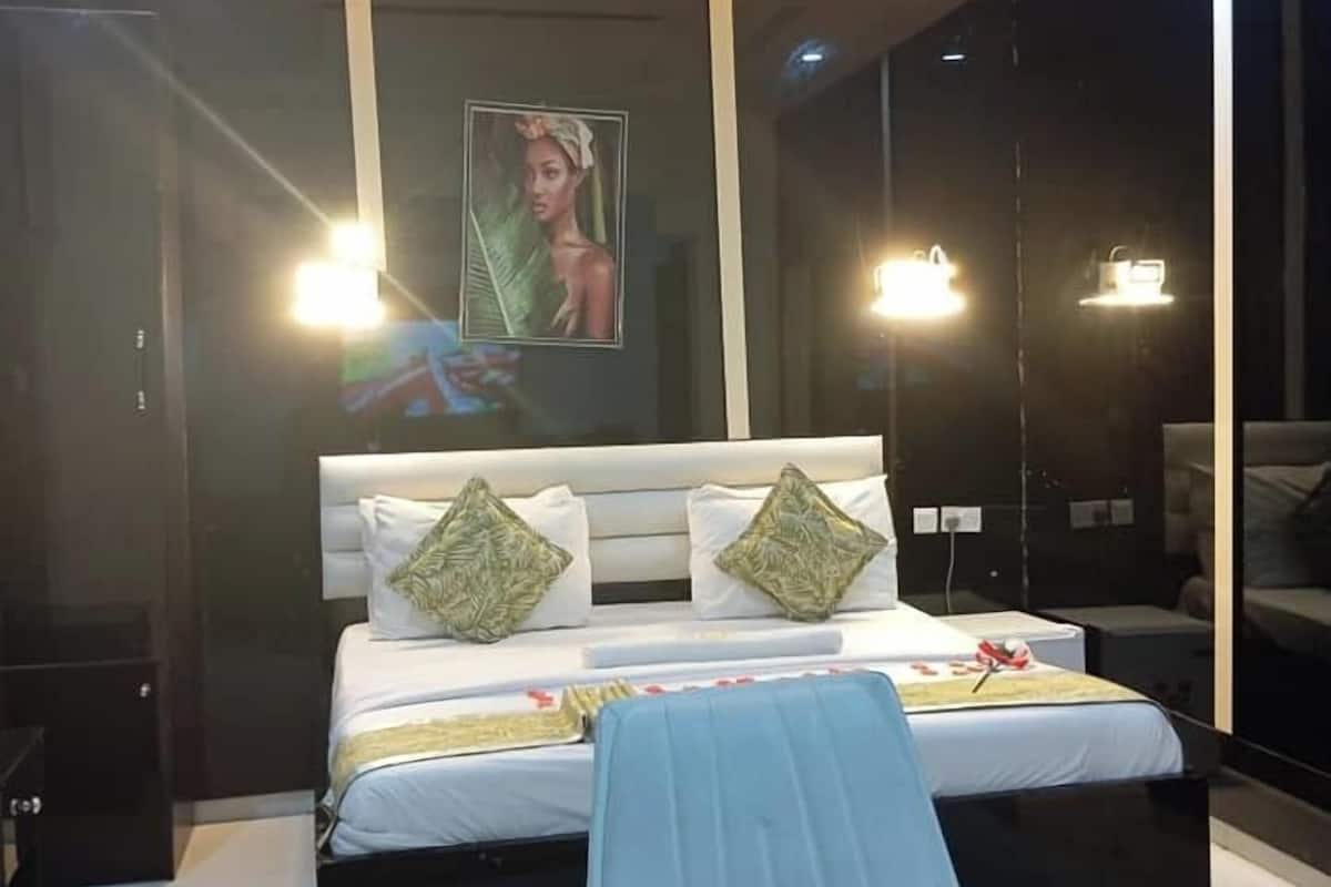 A modern bedroom with a large bed, a chair, and a painting on the wall.