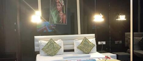 A modern bedroom with a large bed, a chair, and a painting on the wall.